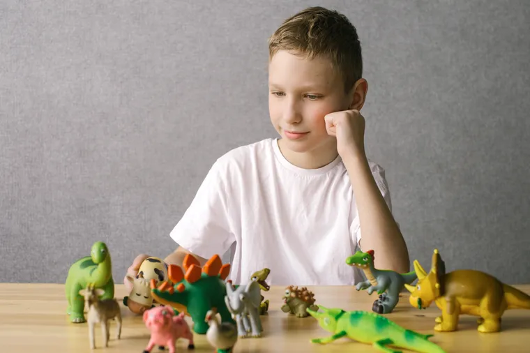 Niño jugando concentrado con animales de juguete sobre una mesa